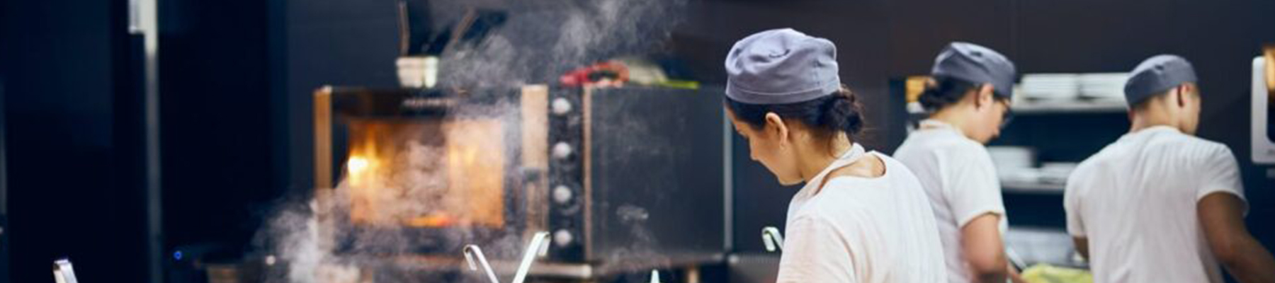 "Professional chefs working in a busy restaurant kitchen with steam rising from freshly prepared dishes.