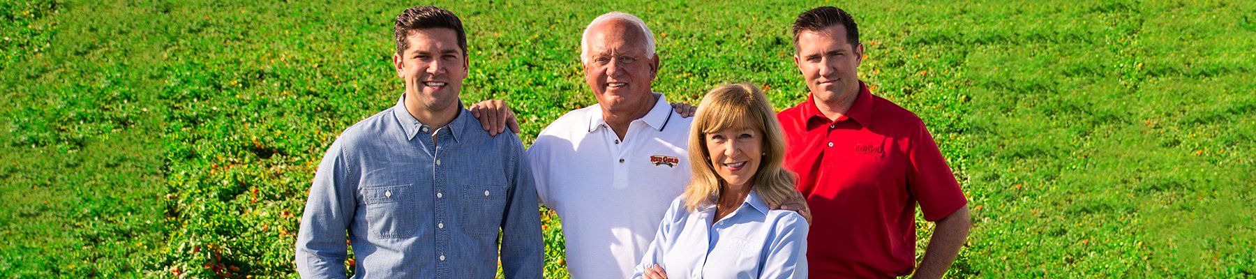 A family of farmers standing proudly in a tomato field, representing a multi-generational farming business.